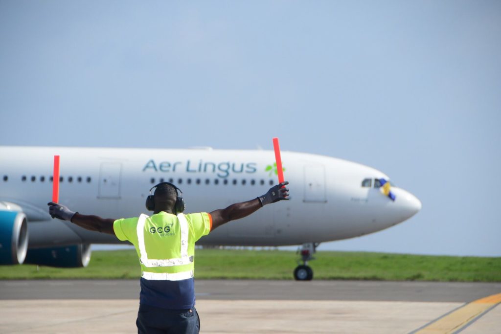 A man directing an aer lingus plane on the runway